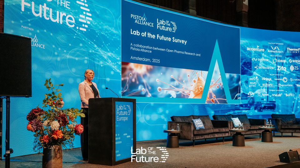 A speaker presenting in front of a large, curved presentation screen at the Lab of the Future Europe Congress. The focal point is the presentation deck, reading "Lab of the Future Survey".