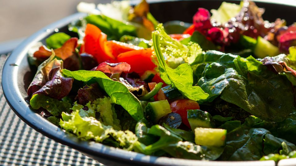 A large, colourful, vegetarian salad in a wide ceramic bowl.