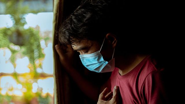 Individual wearing a blue surgical mask, indicating COVID-19 pandemic. 