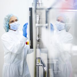 Scientist in sterile protective gear operating bioprocessing equipment in a cleanroom laboratory 