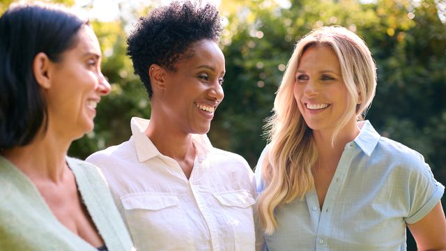 Three women smiling outdoors, representing community and support for PCOS awareness. 