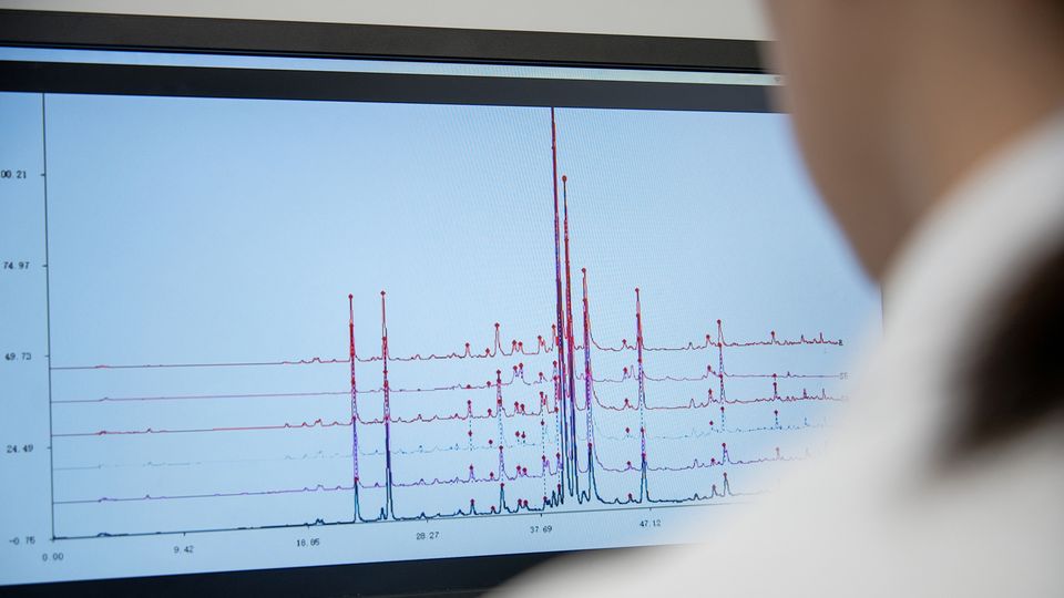 XRD data graphs displayed on a computer screen with the back of a scientist who is looking at it out of focus in the foreground.